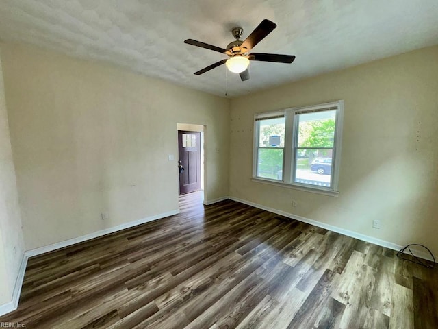 spare room with dark wood-type flooring, baseboards, and ceiling fan
