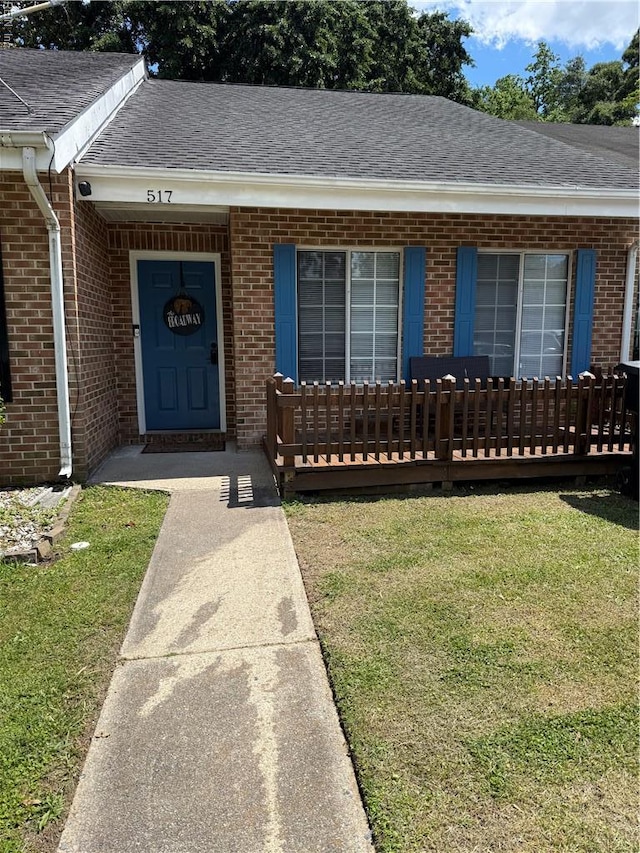 517 Lanier Cres, Portsmouth, VA 23707 - view of exterior entry featuring a lawn, a shingled roof, and brick siding