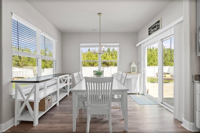 dining area with healthy amount of natural light, a chandelier, and wood finished floors