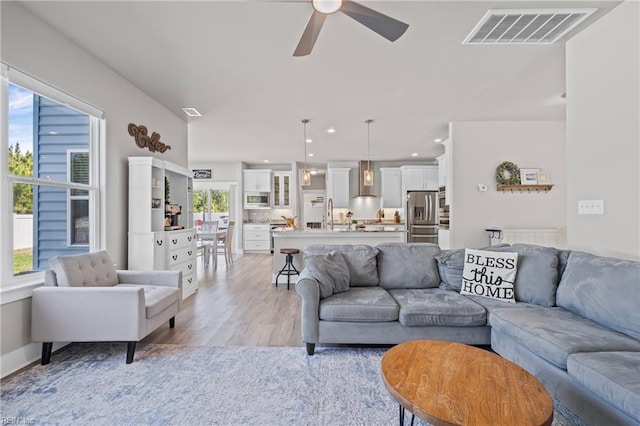 living room with ceiling fan and light wood finished floors