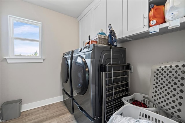 washroom featuring separate washer and dryer, cabinet space, light wood-style floors, and baseboards