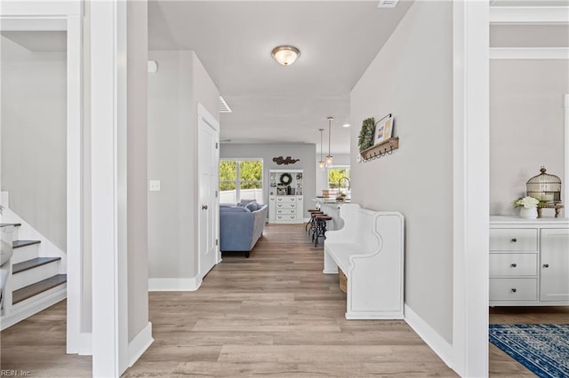 hallway featuring light wood-type flooring, baseboards, and stairs