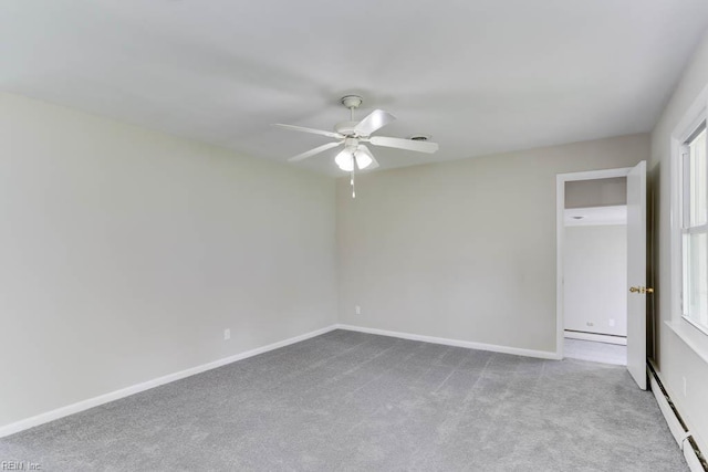 carpeted empty room featuring a baseboard heating unit, a ceiling fan, baseboards, and plenty of natural light