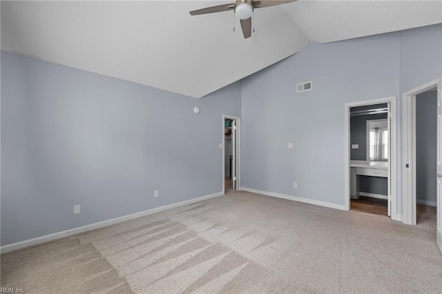 unfurnished bedroom with a walk in closet, carpet, high vaulted ceiling, baseboards, and ensuite bath