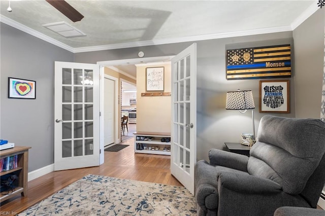 sitting room with french doors, ornamental molding, wood finished floors, and baseboards