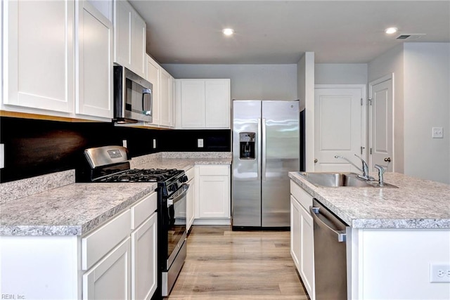 307 Lorraine Dr, Williamsburg, VA 23185 - kitchen featuring stainless steel appliances, a sink, light wood-style flooring, white cabinets, and a center island with sink