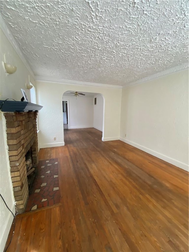 3814 Lenoir Cir, Norfolk, VA 23513 - unfurnished living room featuring arched walkways, wood-type flooring, a brick fireplace, baseboards, and a textured ceiling