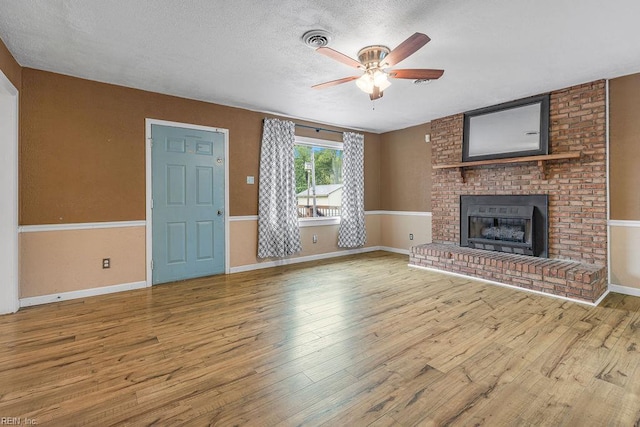 27195 Dogwood Bend Rd, Franklin, VA 23851 - unfurnished living room featuring a ceiling fan, wood finished floors, a brick fireplace, a textured ceiling, and baseboards