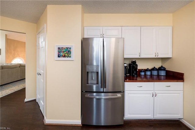 kitchen featuring stainless steel fridge, dark wood-type flooring, butcher block countertops, and white cabinets