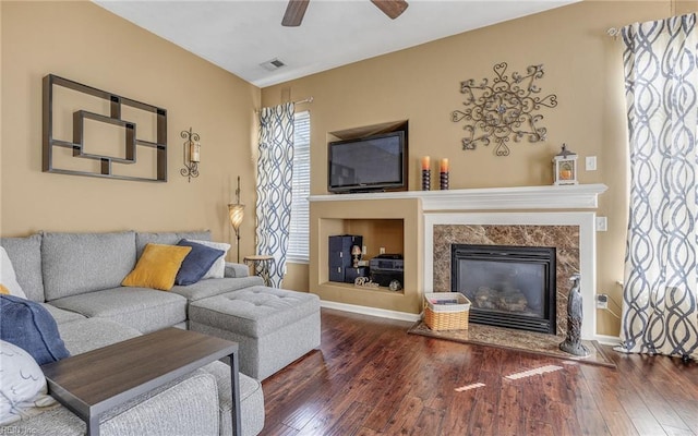 living room featuring hardwood / wood-style floors, ceiling fan, a high end fireplace, and baseboards