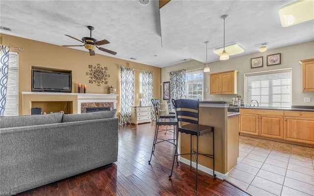 kitchen featuring a breakfast bar area, ceiling fan, light brown cabinetry, a center island, and hardwood / wood-style floors