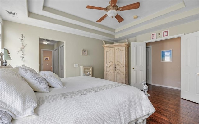 bedroom with dark wood-type flooring, a raised ceiling, baseboards, and ceiling fan