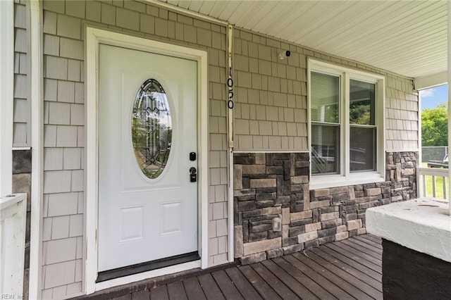 view of exterior entry featuring a porch and stone siding