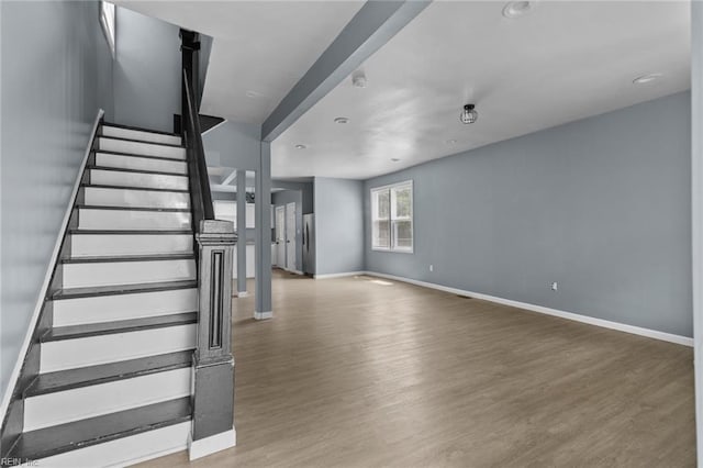 unfurnished living room with wood finished floors, baseboards, stairs, and recessed lighting
