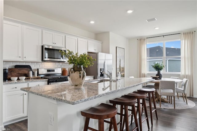 104 Genoa Dr, Elizabeth City, NC 27909 - kitchen featuring stainless steel appliances, white cabinetry, backsplash, dark wood-type flooring, and a breakfast bar