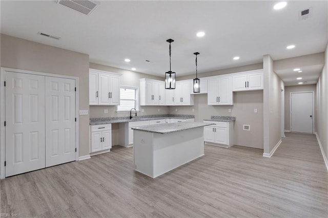 503 Middlesex St, Norfolk, VA 23523 - kitchen with a kitchen island, a sink, baseboards, light wood finished floors, and white cabinets