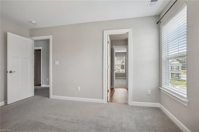 unfurnished bedroom with carpet floors, baseboards, and ensuite bath