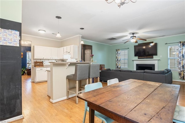 5049 Kelso St, Suffolk, VA 23435 - dining room with light wood finished floors, a fireplace, ceiling fan, and ornamental molding