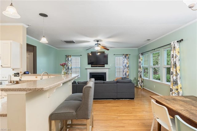 5049 Kelso St, Suffolk, VA 23435 - kitchen with light wood-type flooring, a breakfast bar area, crown molding, white cabinets, and a ceiling fan
