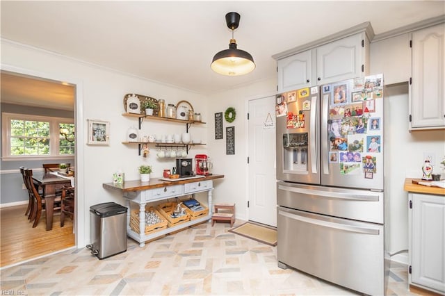 kitchen featuring stainless steel refrigerator with ice dispenser, pendant lighting, ornamental molding, light countertops, and baseboards