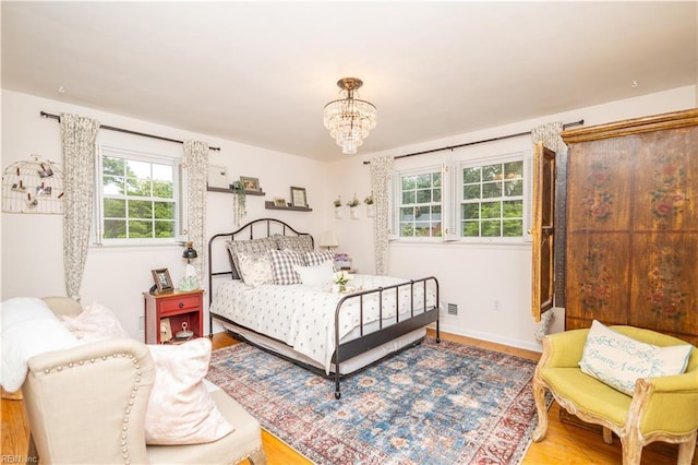 bedroom featuring wood finished floors, a chandelier, and baseboards