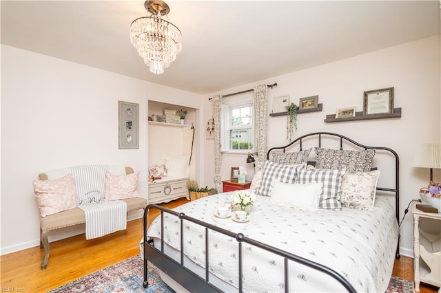 bedroom featuring wood finished floors, a chandelier, and baseboards