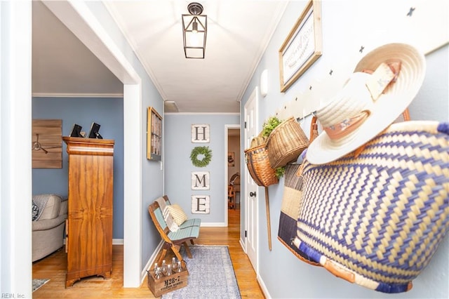 hall with wood finished floors, ornamental molding, and baseboards