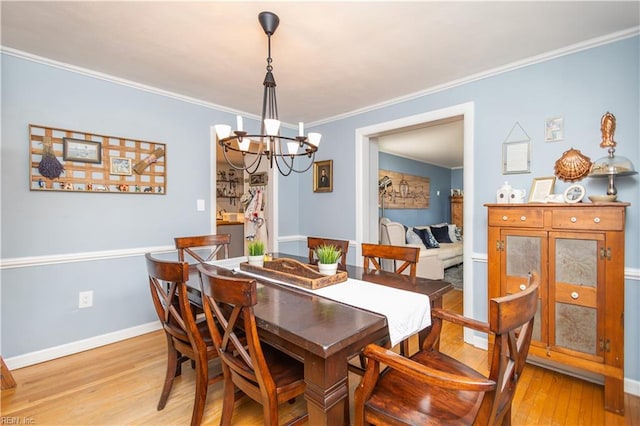 dining room featuring a chandelier, light wood-style flooring, crown molding, and baseboards