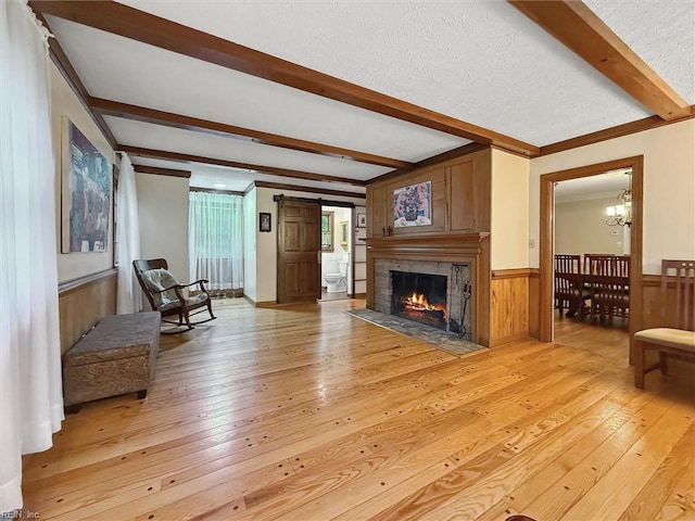 122 Archer Rd, Newport News, VA 23606 - living room featuring beam ceiling, light wood-type flooring, a chandelier, wainscoting, and a fireplace with flush hearth