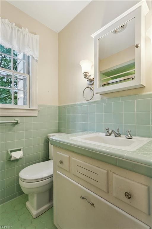 122 Archer Rd, Newport News, VA 23606 - bathroom with tile patterned floors, vanity, toilet, tile walls, and a wainscoted wall