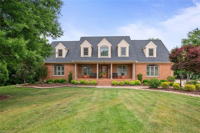 cape cod home featuring a porch, brick siding, and a front yard