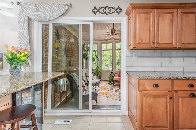 doorway with light tile patterned floors, ceiling fan, and beverage cooler