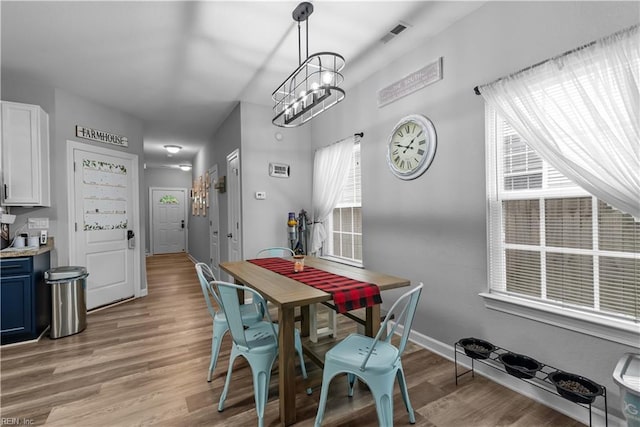 dining room featuring light wood finished floors, a chandelier, and baseboards