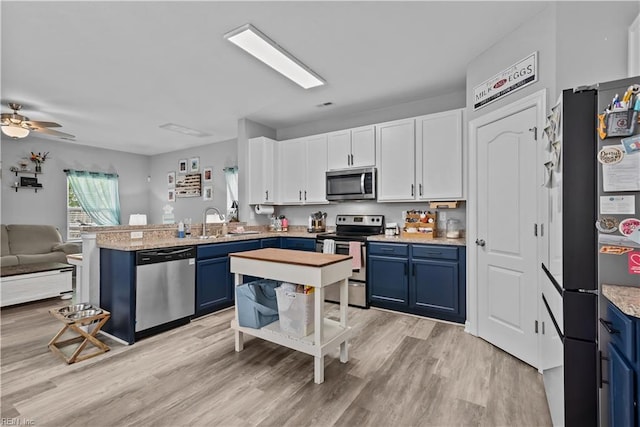 kitchen featuring appliances with stainless steel finishes, blue cabinetry, a peninsula, and open floor plan