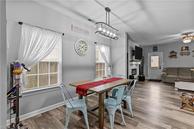 dining area featuring plenty of natural light, wood finished floors, a ceiling fan, and a fireplace