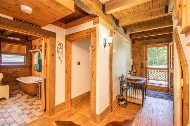hallway with wood ceiling, beamed ceiling, wood finished floors, and wood walls