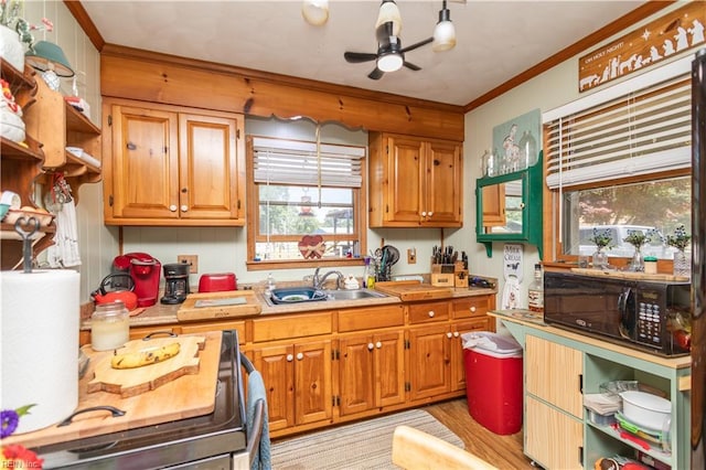 kitchen featuring black microwave, a sink, light countertops, ornamental molding, and brown cabinetry