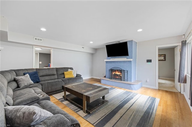 living room with a brick fireplace, light wood-type flooring, recessed lighting, and baseboards