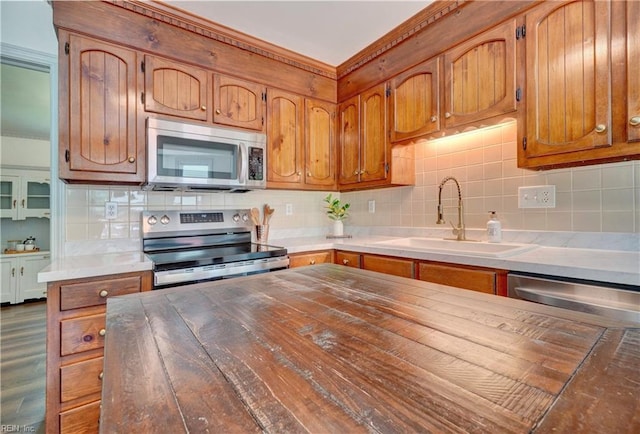 1305 Oak Ridge Dr, Chesapeake, VA 23322 - kitchen featuring appliances with stainless steel finishes, a sink, backsplash, crown molding, and brown cabinetry