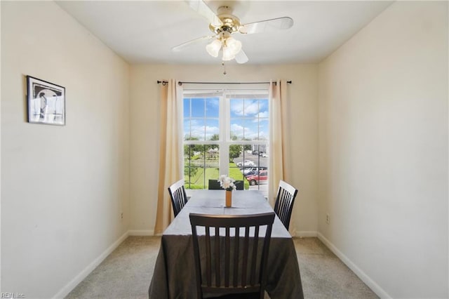 dining room featuring light carpet, baseboards, and a ceiling fan