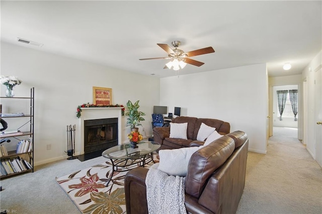 living area with light carpet, a ceiling fan, a fireplace with flush hearth, and baseboards