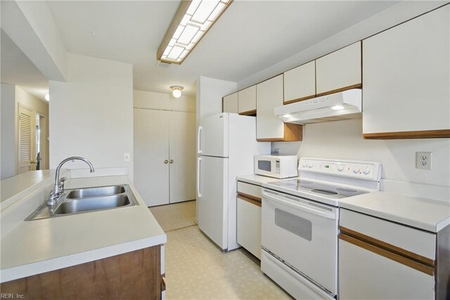 kitchen with white appliances, under cabinet range hood, a sink, light floors, and light countertops