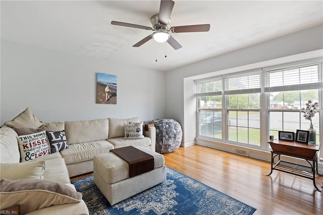 living area featuring wood finished floors, ceiling fan, and baseboards