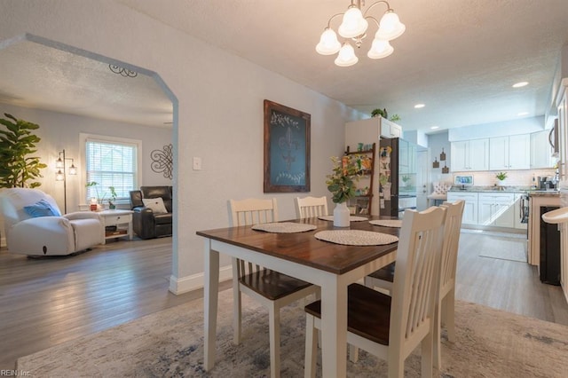 310 Manteo Ave, Hampton, VA 23661 - dining room featuring light wood-style flooring, a textured ceiling, arched walkways, a chandelier, and baseboards