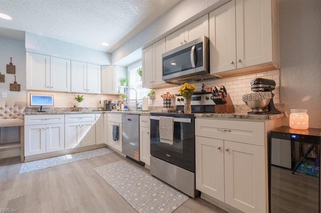 310 Manteo Ave, Hampton, VA 23661 - kitchen featuring stainless steel appliances, a sink, light wood-type flooring, a textured ceiling, and white cabinetry