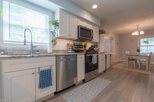 310 Manteo Ave, Hampton, VA 23661 - kitchen with appliances with stainless steel finishes, a sink, white cabinetry, decorative backsplash, and light wood-style flooring