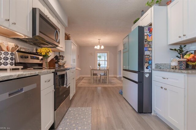 310 Manteo Ave, Hampton, VA 23661 - kitchen featuring appliances with stainless steel finishes, backsplash, light wood finished floors, a chandelier, and white cabinets