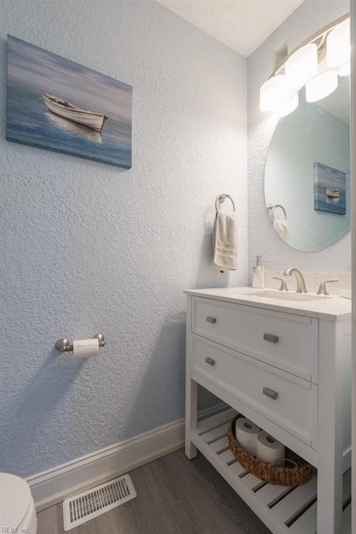 310 Manteo Ave, Hampton, VA 23661 - bathroom with wood finished floors, vanity, baseboards, toilet, and a textured wall