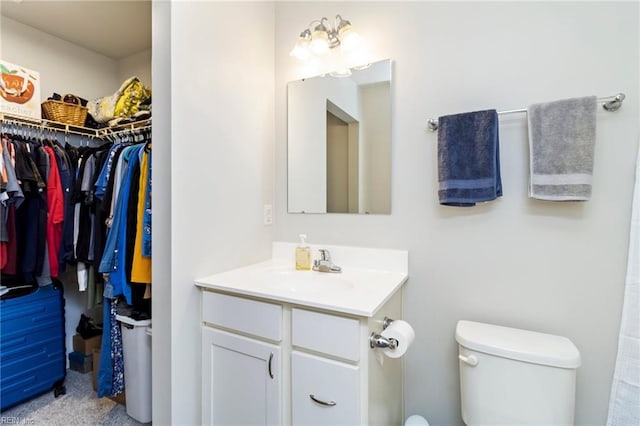 bathroom with toilet, vanity, and a spacious closet