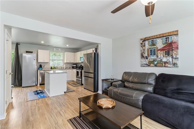 living room with light wood-style flooring, a ceiling fan, and recessed lighting